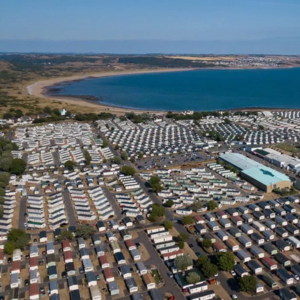 image depicting a caravan site next to the sea on a bay