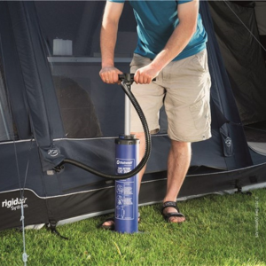 an image showing a tent and a man pumping up the air into the air beams of the tent on green grass