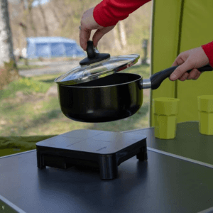 an image showing a camping table with a 1 burner camping stove and a sauce pan being placed on top