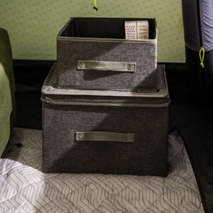 an image of 2 storage boxes set on a tent carpet made from a grey wool like fabric and green fabric handles. 