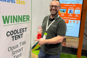 An image showing a man in front of the winning banner holding an award