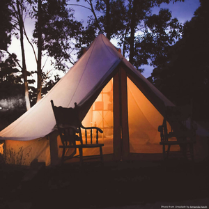 an image at duck of a tipi tent lit up inside with a warm orange light. Outside sits two wooden rocking chairs