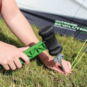 an image showing a man hammering in a tent peg and guyline on grass. The hammer has a green plastic handle with black hammer end. 