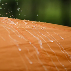 an image of orange canvas being sprayed from the left top corner with water beading on the fabric